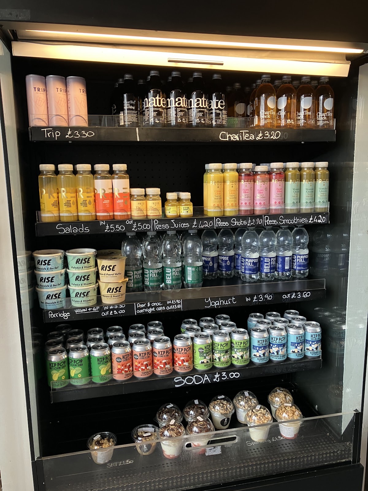 Lit fridge display of bottled juices and canned soft drinks